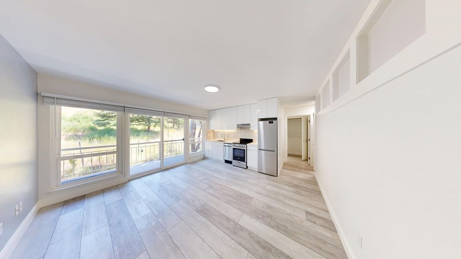 A spacious living room with a kitchen in the background.